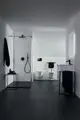 Moderne Dusche in weißem Raum mit schwarzem Duschkopf und Handbrause. Ideal Standard Sanitärgegenstände, inklusive zwei Wand-WC und Waschbecken im minimalistischen Design.